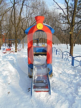 Red children's slide as a locomotive in the snow park area of Ã¢â¬â¹Ã¢â¬â¹the city